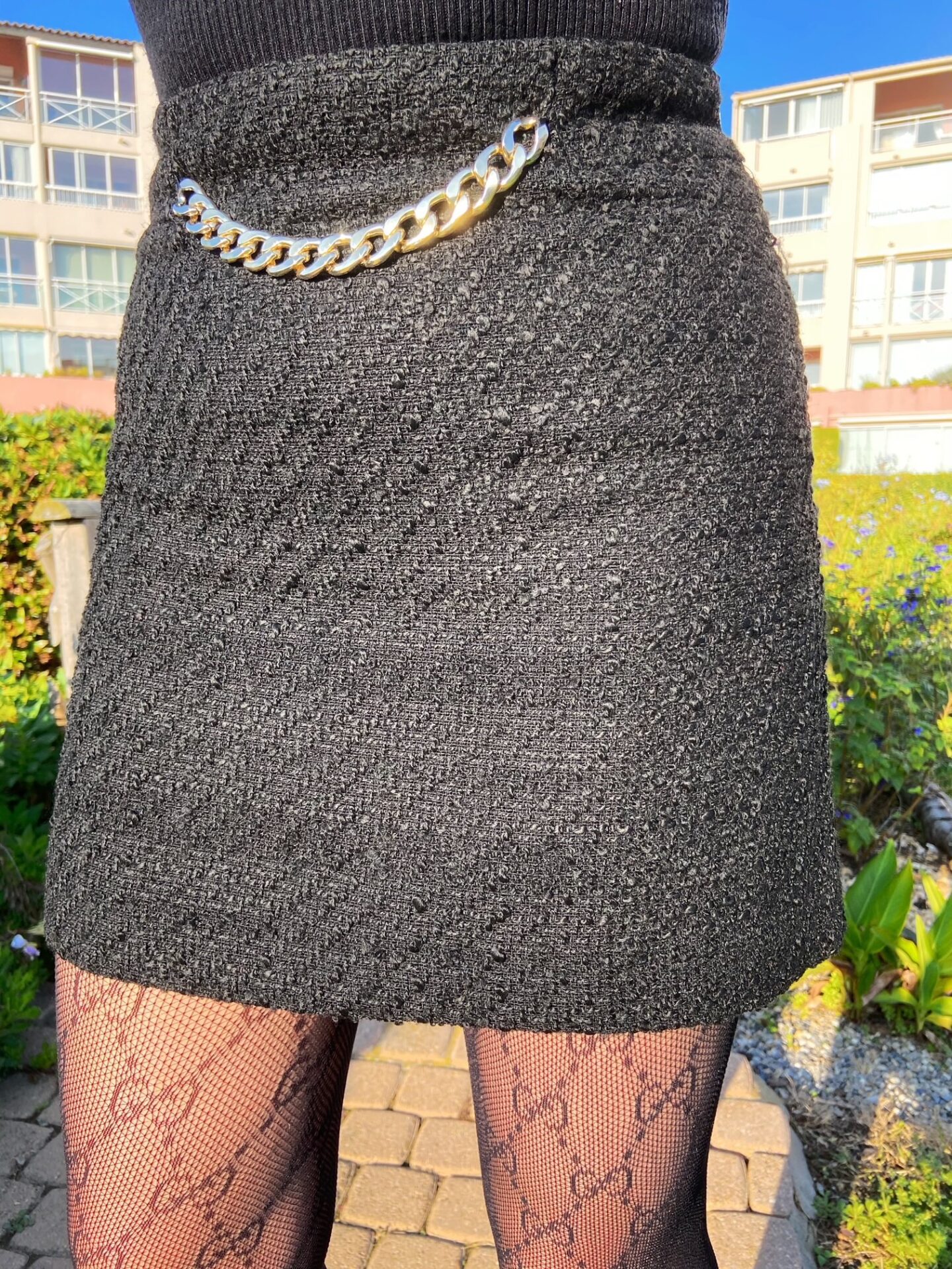 Black tweed skirt with chain and luxury Gucci tights for a chic look